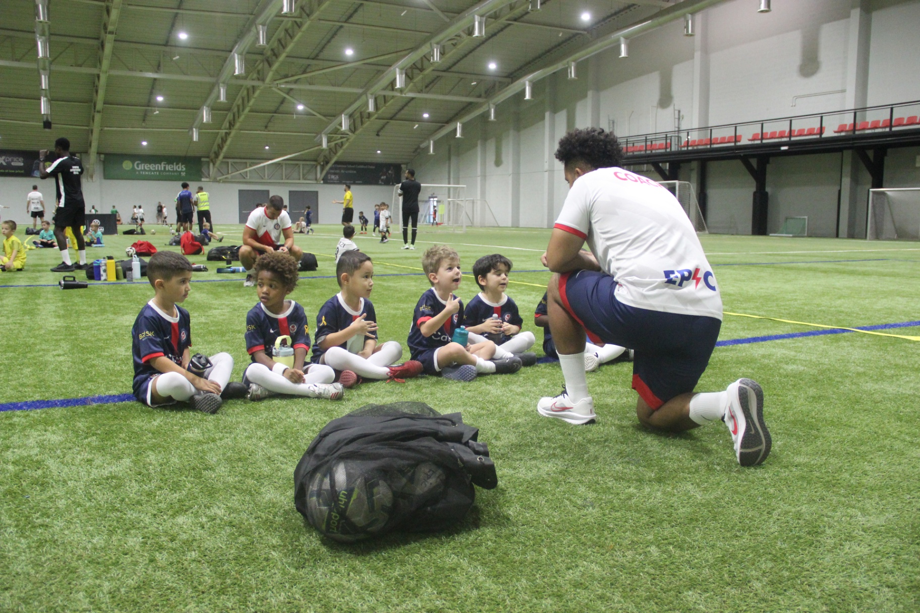 Coach talking to young players during an indoor football session in Dubai